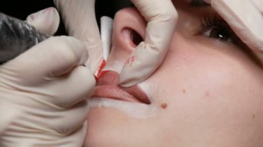 Mikro patenli dudak dövmesi ve kozmetoloji kliniğindeki dudak rengini düzelten kırmızı pigment. Kalıcı makyaj dudakları prosedürü. Dövme makinesiyle dudaklara pigment makyaj uygulanıyor.