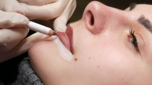 Microblading, micropigmentatie lippen werken stroom in een schoonheidssalon. Vrouw met een met potlood getrokken en getinte lip, die zich voorbereidt op semi-permanente make-up — Stockvideo