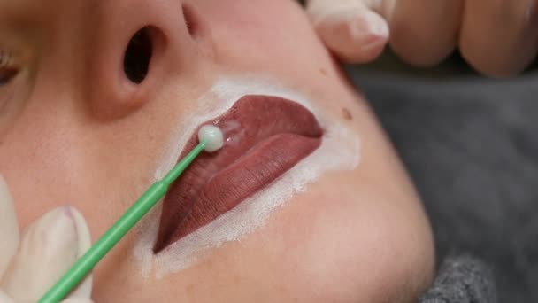 Beautician mästare tillämpar speciell anestesi på läpparna. Förberedelse för permanent läppmakeup. Modern ansiktstatuering — Stockvideo