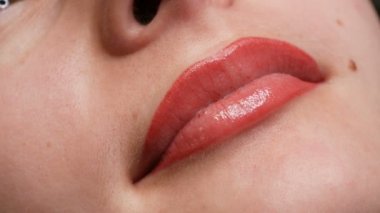 Genç ve güzel bir kızın yüzü. Kalıcı dudak makyajının son sonucu. Açık kırmızı dudaklar, kapatın.