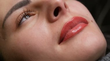 Genç ve güzel bir kızın yüzü. Kalıcı dudak makyajının son sonucu. Açık kırmızı dudaklar, kapatın.