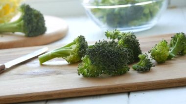 Mutfak tahtasına çiğ yeşil brokolili lahana kes. Aşçı bıçakla sebze doğradı. Vejetaryen yemeği.