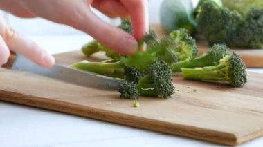 Mutfak tahtasındaki taze yeşil brokolili lahanayla kesilmiş kadın elleri. Aşçı bıçakla sebze doğradı. Vejetaryen yemeği.