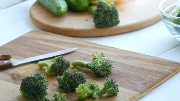 Mutfak tahtasına çiğ yeşil brokolili lahana kes. Aşçı bıçakla sebze doğradı. Vejetaryen yemeği. — Stok video