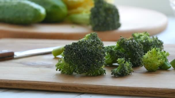 Нарізати сиру свіжу зелену капусту брокколі на кухонній дошці. Готуйте нарізані овочі ножем. Веганська їжа . — стокове відео