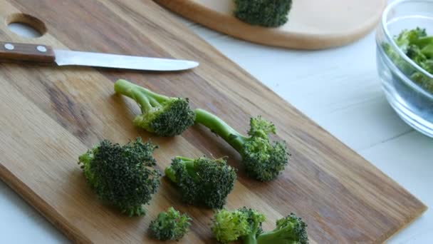 Frischen Brokkoli roh auf einem Küchenbrett schneiden. Gemüse mit einem Messer in Stücke schneiden. Veganes Essen. — Stockvideo