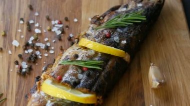 Bir dilim limonla doldurulmuş ve biberiye tütsülenmiş uskumru filizi ile süslenmiş kiraz domatesleri, sarımsak, kaba tuz ve biber ve zeytinyağı yanında ahşap bir doğrama tahtasının üzerinde