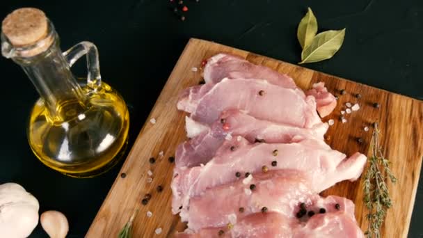 Trozos frescos de carne de tocino de cerdo en un tablero de cocina de madera en un estilo rústico. Ajo, rama de romero, sal gruesa, pimienta, aceite de oliva. Cocina casera . — Vídeos de Stock