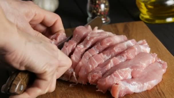 Female hands of a cook cut fresh pieces of pork bacon meat on a wooden kitchen board in rustic style with a large kitchen knife — Stock Video