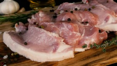 Ahşap mutfak tahtasının üzerinde domuz pastırması taze dilimler. Sarımsak, biberiye dalı, kaba tuz, biber, zeytinyağı. Ev yapımı yemek..