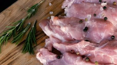 Ahşap mutfak tahtasının üzerinde domuz pastırması taze dilimler. Sarımsak, biberiye dalı, kaba tuz, biber, zeytinyağı. Ev yapımı yemek..