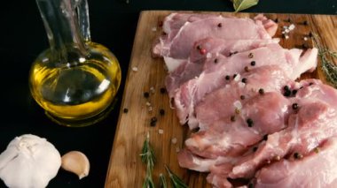Ahşap mutfak tahtasının üzerinde domuz pastırması taze dilimler. Sarımsak, biberiye dalı, kaba tuz, biber, zeytinyağı. Ev yapımı yemek..