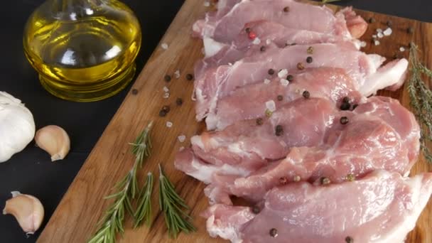 Grand morceau rose frais de viande de porc au bacon sur une planche à découper de cuisine maison dans un style rustique décoré de poivre noir et rouge et de gros sel — Video