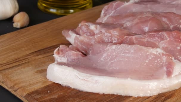 Fresh large pink piece of bacon pork meat on a cutting board of home cooking in a rustic style — Stock Video