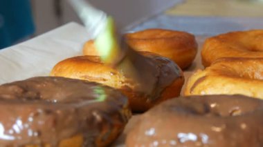 Özel silikon mutfak fırçası büyük bir kızarmış çöreğe çikolata kreması sürer.