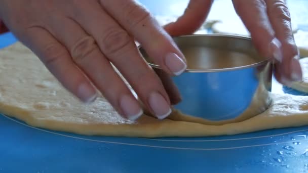 As mãos femininas fazem formas para futuros donuts com um anel redondo especial em um tapete de silicone especial para amassar a massa. Tecnologia moderna na cozinha — Vídeo de Stock