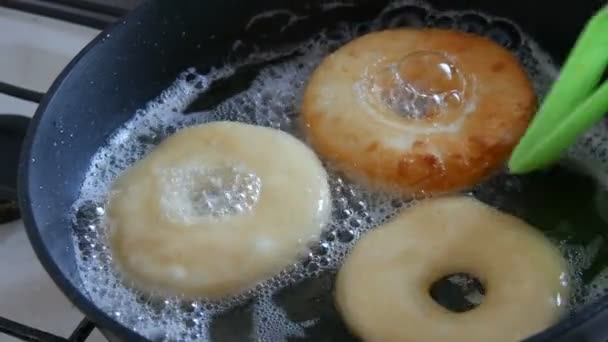 Deliciosas rosquillas fritas en una sartén. Las rosquillas grandes son fritas en el aceite caliente en la cacerola. Hornear en casa — Vídeos de Stock