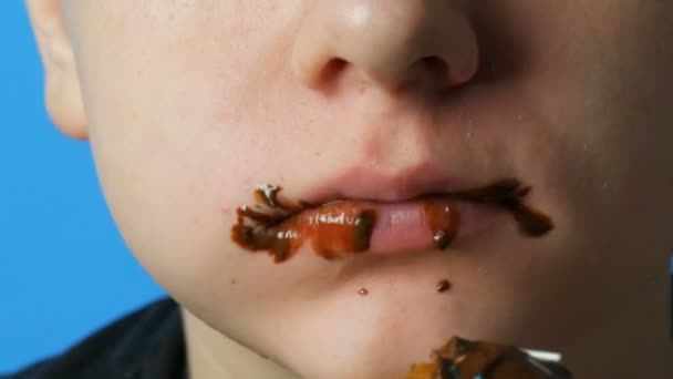 Tiener jongen vuile mond eet chocolade vet donut. Schadelijk zoet, junk food. — Stockvideo