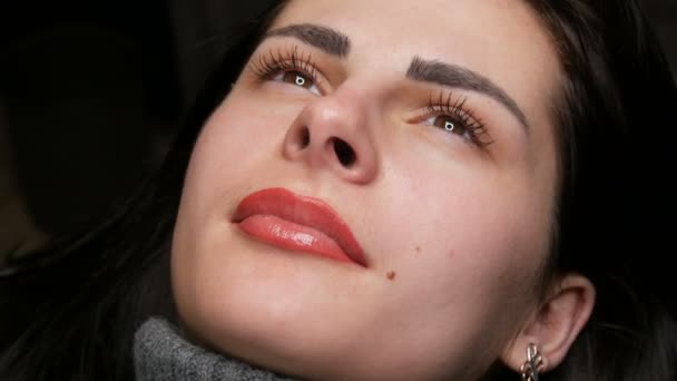 Face of a young beautiful girl. Final result of permanent lip makeup. Girl light red lips close up — Stockvideo