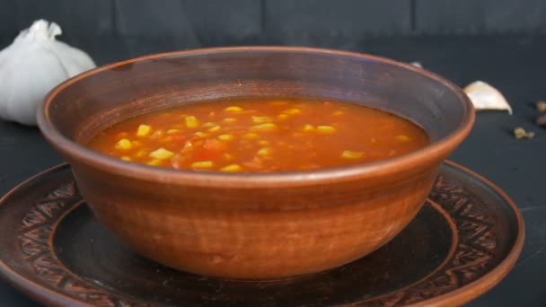 Sopa de tomate vermelho cozida quente com vapor de milho em uma placa de barro marrom em um estilo rústico — Vídeo de Stock