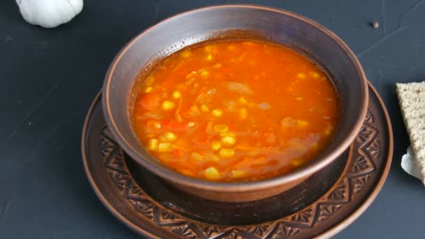 Sopa de tomate rojo hervido caliente con vapor de maíz en un plato de arcilla marrón en un estilo rústico — Vídeo de stock