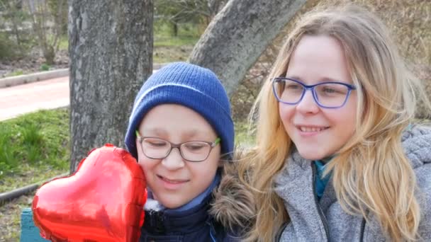 Gözlüklü komik anne ve oğlunun portresi, ilkbaharda parkta gülümsüyor. Anneler Günü, tebrikler, kalp şeklinde balon.. — Stok video