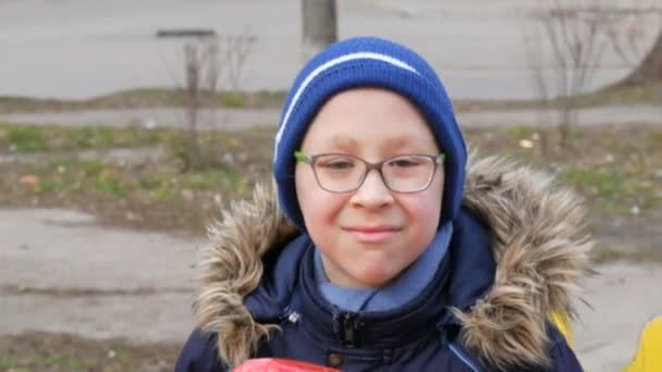 Leuke vrolijke jongen tiener van tien jaar in bril speelt en rijdt op een schommel in de speeltuin in het vroege voorjaar — Stockvideo