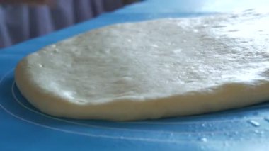 Dişi eller hamuru yoğurmak için özel silikon bir paspasın üzerine merdaneyle hamuru yuvarlıyor. Mutfakta modern teknoloji