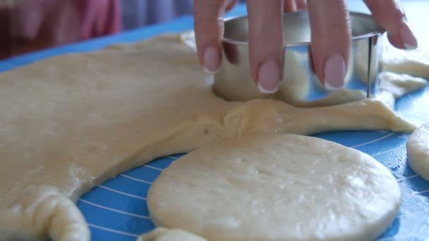 As mãos femininas fazem formas para futuros donuts com um anel redondo especial em um tapete de silicone especial para amassar a massa. Tecnologia moderna na cozinha — Vídeo de Stock