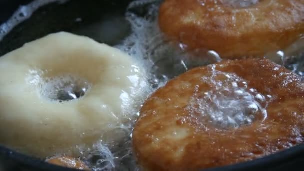맛있는 도넛 이 프라이팬에서 튀기고 있습니다. 큰 도넛을 냄비에 넣고 뜨거운 기름에 튀 깁니다. 집에서 구운 빵 — 비디오