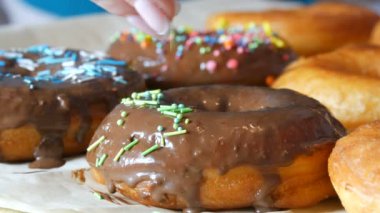 Masada üst üste büyük renkli taze kızarmış çörekler. Çikolata kremalı güzel bir donut, şekerlerin dekorasyonu için özel renkli bir toz serpiştirilir.