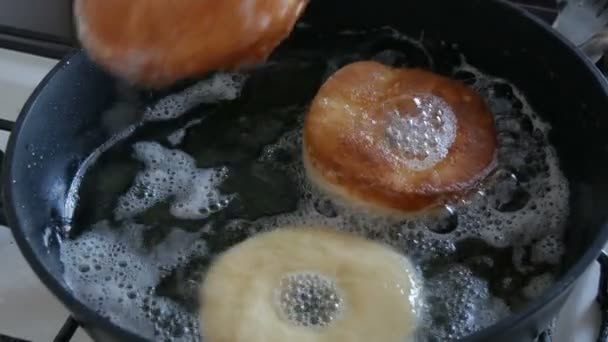 Deliciosos donuts fritando em uma panela. Os grandes donuts fritam-se no óleo quente em uma panela. Cozimento caseiro — Vídeo de Stock