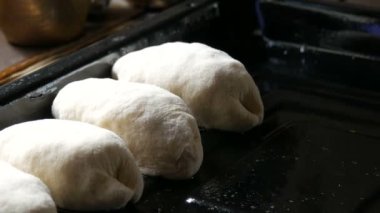 Kadın eli, ev yapımı hamur pastaları özel bir metal yaprak üzerine koyuyor. Formdaki hamur fırın için hazır.