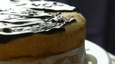 Manzarayı kapat. Sünger kekine çikolata jölesi süren bir kadın. Pastanın üzerine kaşık ile kadın el kremi dök ve portakallı bisküvi veya mutfakta kek hamuru sürmeye başla.