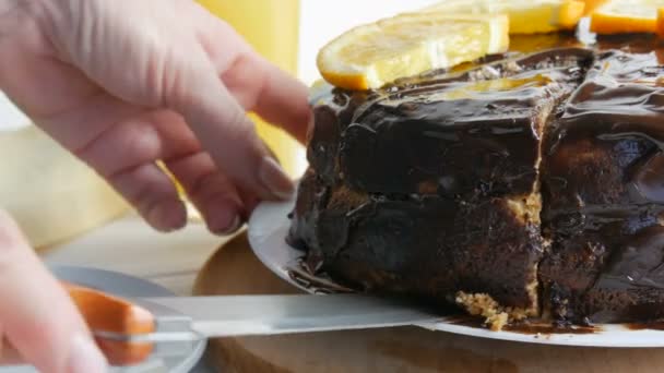 女性の手はオレンジとチョコレートアイシングのスライスとスポンジケーキの大きな作品を取ります.甘い糖尿病食品 — ストック動画