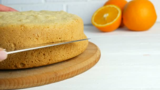 De handen van een bakkersvrouw met een mes snijden een sinaasappelkoekje of een taartdeeg in de keuken. Het maken van zoete zelfgemaakte taart. — Stockvideo