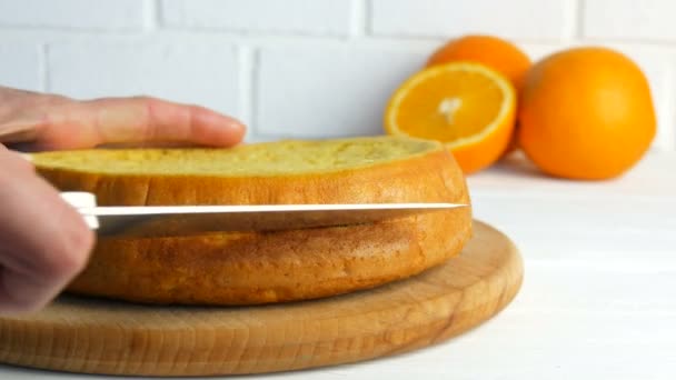 As mãos de uma cozinheira cozinheira com uma faca cortam um biscoito de laranja ou massa de pão de esponja na cozinha. Fazendo torta caseira doce . — Vídeo de Stock