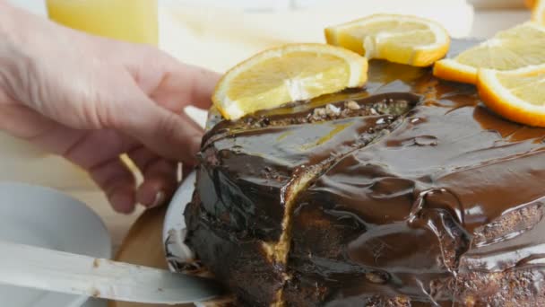 女性の手はオレンジとチョコレートアイシングのスライスとスポンジケーキの大きな作品を取ります.甘い糖尿病食品 — ストック動画