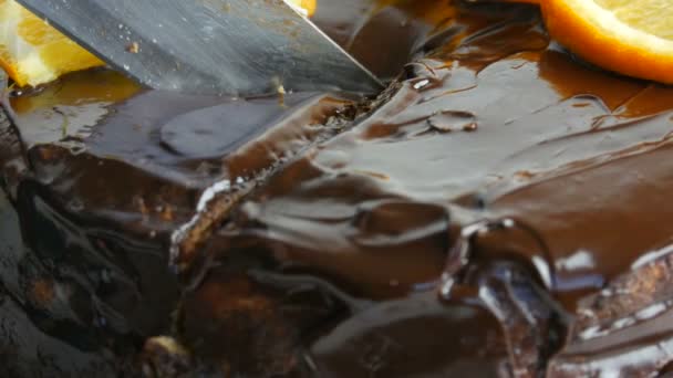 Egy kés elvág egy finom kekszet. Közelkép a házi csokoládé torta cukormázzal és narancs szeletek. Cukorbeteg ételek. — Stock videók