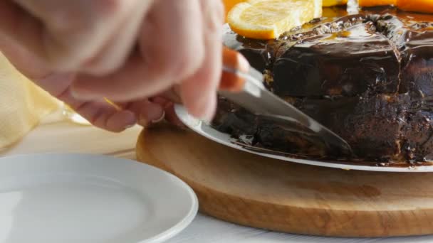 As mãos femininas tomam um grande pedaço de bolo de esponja com fatias de laranja e cobertura de chocolate. Alimentos doces para diabéticos — Vídeo de Stock