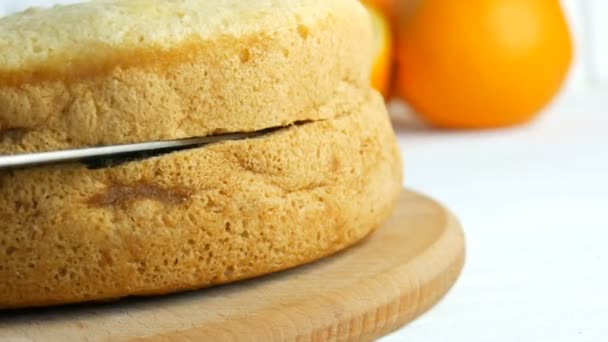 Hände einer Bäckerfrau schneiden in der Küche mit einem Messer einen Orangenkeks oder Biskuitteig an. Herstellung von süßen hausgemachten Kuchen. — Stockvideo