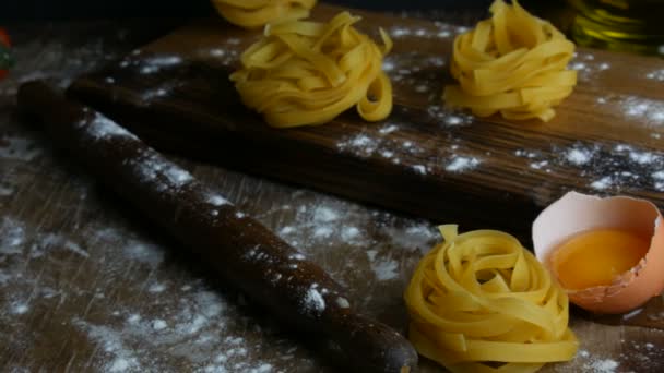 Olasz sodort friss fettuccine tészta. Spagetti Tagliatelle fészkel egy fa konyhaasztalon mellett törött tojássárgája, liszt és olívaolaj rusztikus stílusban. Nemzeti olasz élelmiszer — Stock videók