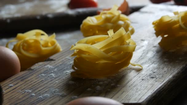 Bir sıra ulusal İtalyan yemeği. Çiğ un ürünleri manzarayı kapatır. Tagliatelle ya da fettuccine pastaları, kırsal tarzda kırılmış yumurta sarısının yanındaki ahşap mutfak tahtasına yuva yapar.. — Stok video