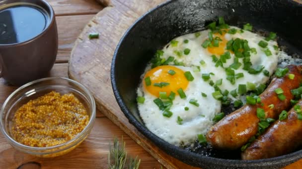 Cup of coffee withFunny food fried eggs with Bavarian white fried sausages and fresh green onions in the form of a face with a smile, next to French mustard. Rustic style of serving food — Stock Video