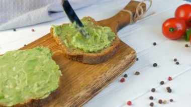 Kızarmış ekmeğin üzerine bıçakla ezilmiş avokado. Kahvaltıda lezzetli avokado tostu yapıyorum. Kiraz domatesli bruschetta ve bıldırcın yumurtası pişirmek. Yakından bak. Sağlıklı vejetaryen yemekleri