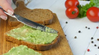 Kızarmış ekmeğin üzerine bıçakla ezilmiş avokado. Kahvaltıda lezzetli avokado tostu yapıyorum. Kiraz domatesli bruschetta ve bıldırcın yumurtası pişirmek. Yakından bak. Sağlıklı vejetaryen yemekleri