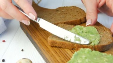 Kızarmış ekmeğin üzerine bıçakla ezilmiş avokado. Kahvaltıda lezzetli avokado tostu yapıyorum. Kiraz domatesli bruschetta ve bıldırcın yumurtası pişirmek. Yakından bak. Sağlıklı vejetaryen yemekleri