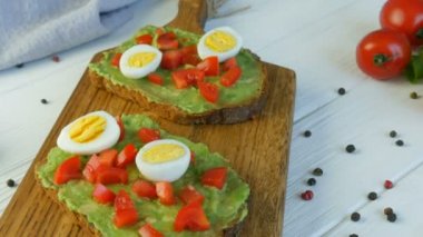 Sağlıklı vejetaryen yemeği. Kavrulmuş kahverengi ekmeğin üzerine avakado ezmesi dök. Kahvaltıda lezzetli avokado tostu yapıyorum. Kiraz domatesli bruschetta ve bıldırcın yumurtası pişiriyorum..