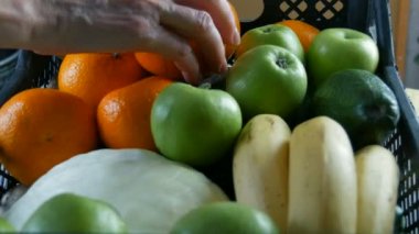 Kadın eli mandalina ve elma alır. Meyve ve sebzeli kutu yakın. Coronavirus salgını ve sosyalleşme sırasında yiyecek dağıtım hizmetleri. İnternetten alışveriş. Yemek Bağışı