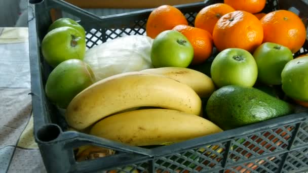 Caja llena con frutas y verduras plátanos manzanas mandarinas repollo de aguacate de cerca. Servicios de entrega de alimentos durante la pandemia de coronavirus y distanciamiento social. Compras en línea. Comidas Donaciones de alimentos — Vídeos de Stock
